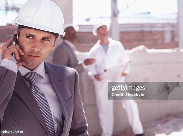 close-up of an architect talking on a mobile phone at a construction site - oficio de diseño fotografías e imágenes de stock