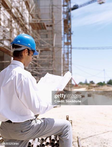 rear view of an architect looking at blueprints at a construction site - design occupation stock pictures, royalty-free photos & images