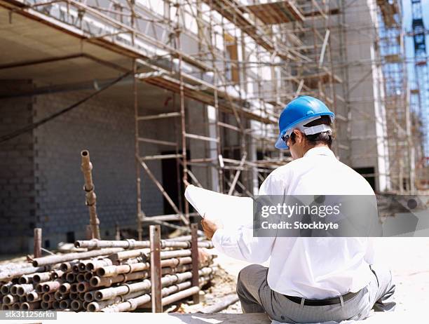 rear view of a male architect holding a blueprint - design occupation fotografías e imágenes de stock