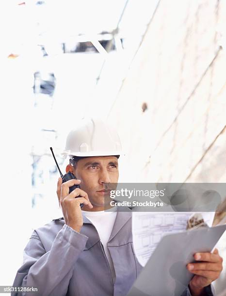 construction worker talking on a walkie-talkie at a construction site - inside the link real estate investment trust properties ahead of interim results stockfoto's en -beelden