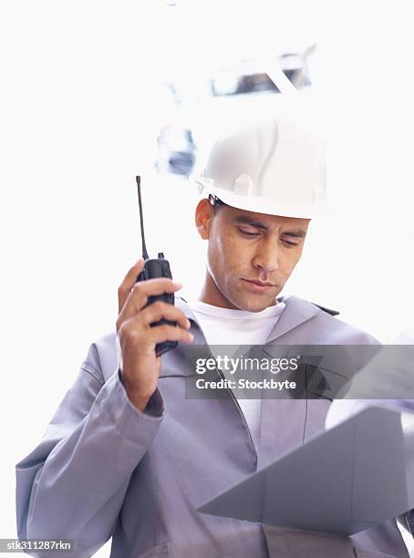 male architect holding a walkie-talkie and looking at a file - oficio de diseño fotografías e imágenes de stock