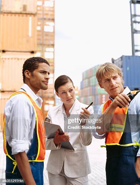 businesswoman talking with two foremen at a commercial dock - transceiver stock pictures, royalty-free photos & images