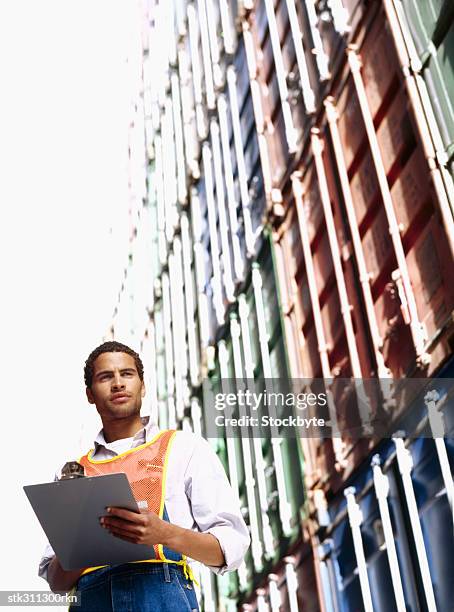 low angle view of a foreman holding a clipboard, standing at a commercial dock - foreman stock pictures, royalty-free photos & images