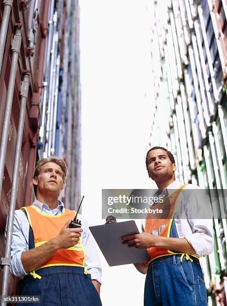 low angle view of two construction workers standing in a commercial dock - transceiver stock pictures, royalty-free photos & images