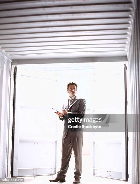 businessman holding a clipboard, standing in a cargo container - inside the link real estate investment trust properties ahead of interim results stockfoto's en -beelden