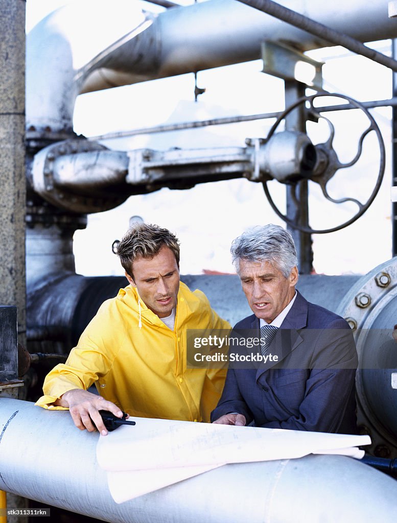 Male engineer and a mechanic discussing a blueprint