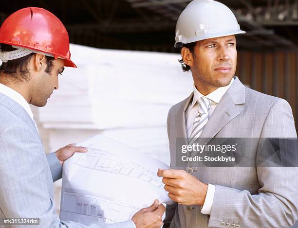 close-up of two male architects holding a blueprint - design occupation fotografías e imágenes de stock