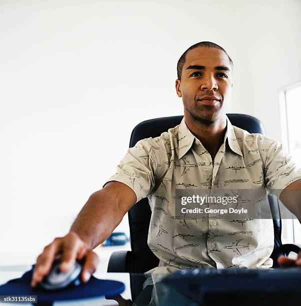 portrait of a man sitting on an office chair working on the computer - meerkamp stockfoto's en -beelden