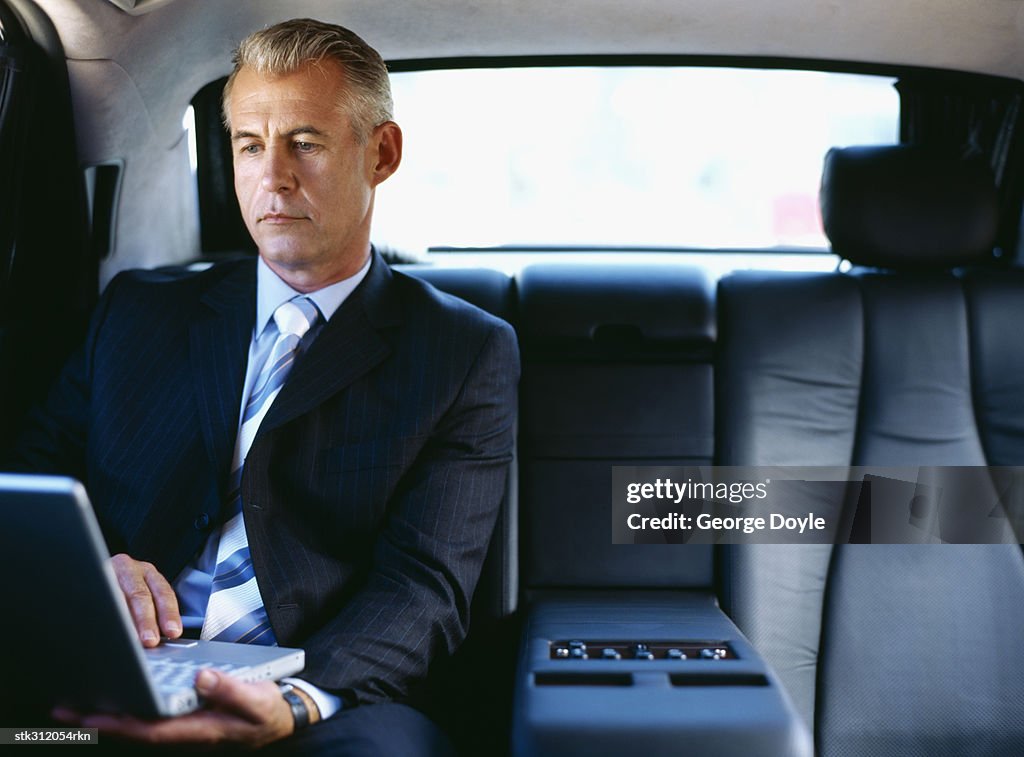 Businessman using a laptop in a car
