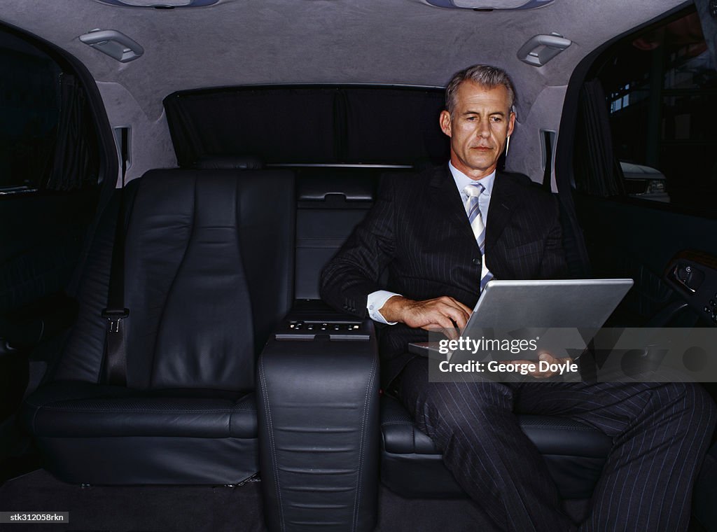 Businessman using a laptop in a car