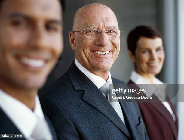 portrait of a businessman standing in between two business executives - between stock-fotos und bilder