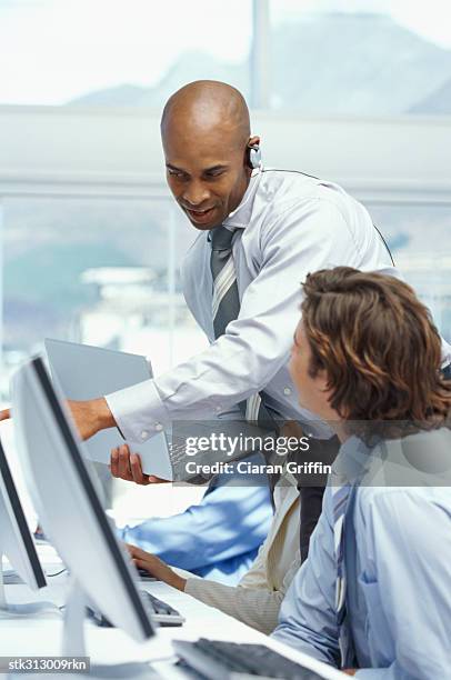 two business executives discussing in front of a computer in a classroom - f100 stock pictures, royalty-free photos & images