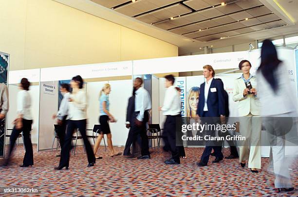 group of business executives walking at an exhibition - foire commerciale photos et images de collection