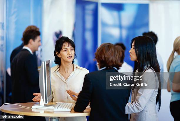 three businesswomen discussing at an exhibition - business people group brown stock pictures, royalty-free photos & images