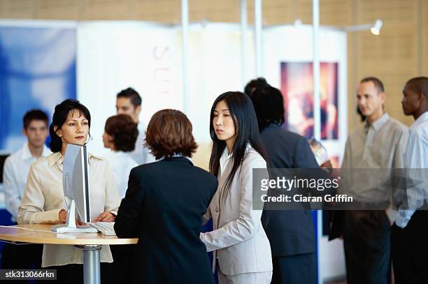 three businesswomen discussing at an exhibition - tradeshow stock pictures, royalty-free photos & images