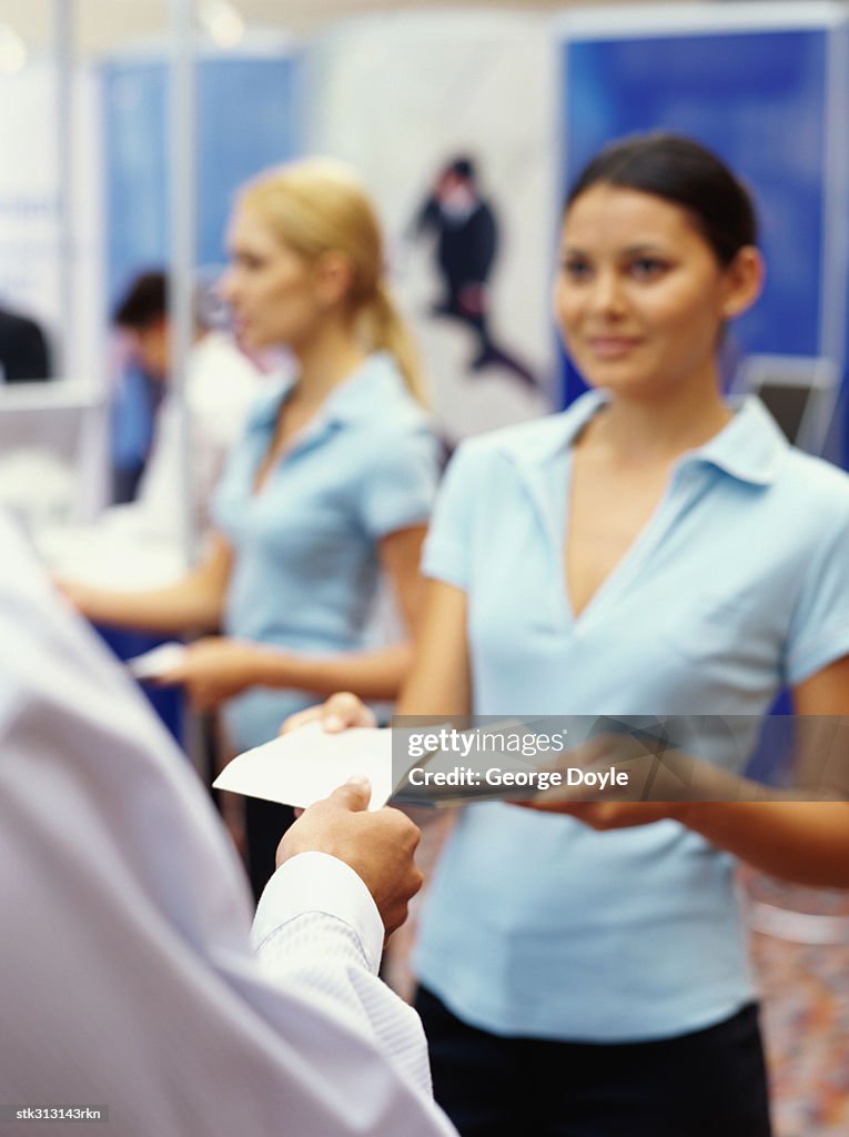 Sales executives distributing brochures to business executives at an exhibition