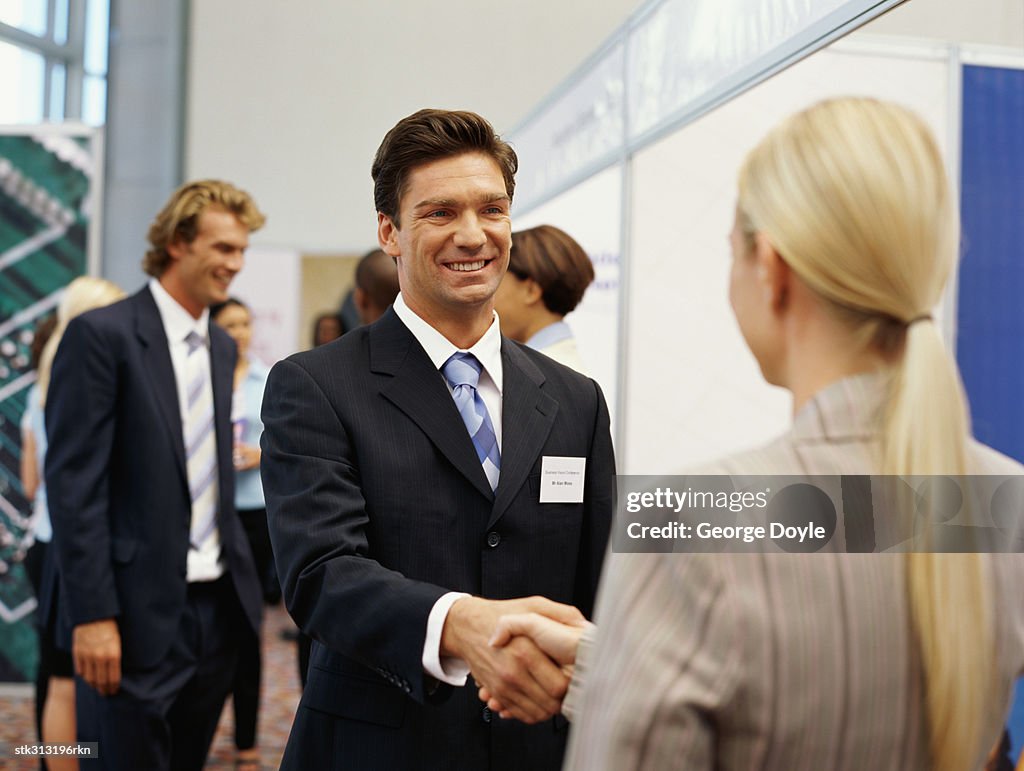 Businessman shaking hands with a businesswoman at an exhibition