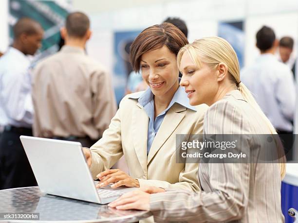 two businesswomen using a laptop at an exhibition - tradeshow ストックフォトと画像