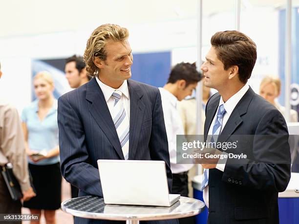 two businessmen discussing in front of a laptop at an exhibition - king juan carlos and queen sofia attends 25th anniversary tribute of seville universal exhibition stockfoto's en -beelden