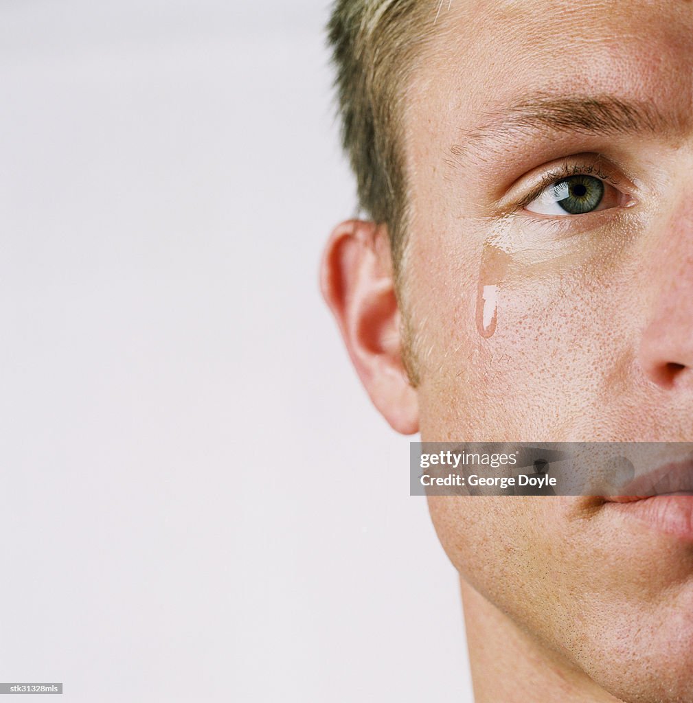 Close-up of the side of a man's face with a tear coming out of his eye