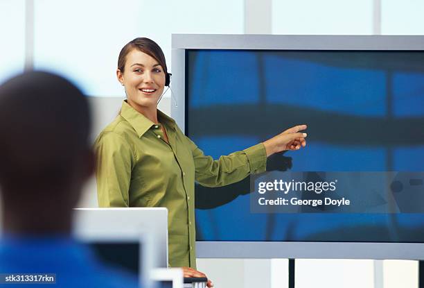 businesswoman pointing to a projection screen at a seminar - presentation of the book scenes de crime au louvre written by christos markogiannakis in paris stockfoto's en -beelden