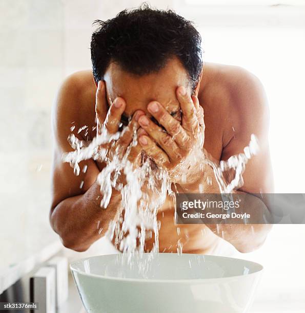 close-up of a man washing his face in a basin full of water - basin ストックフォトと画像