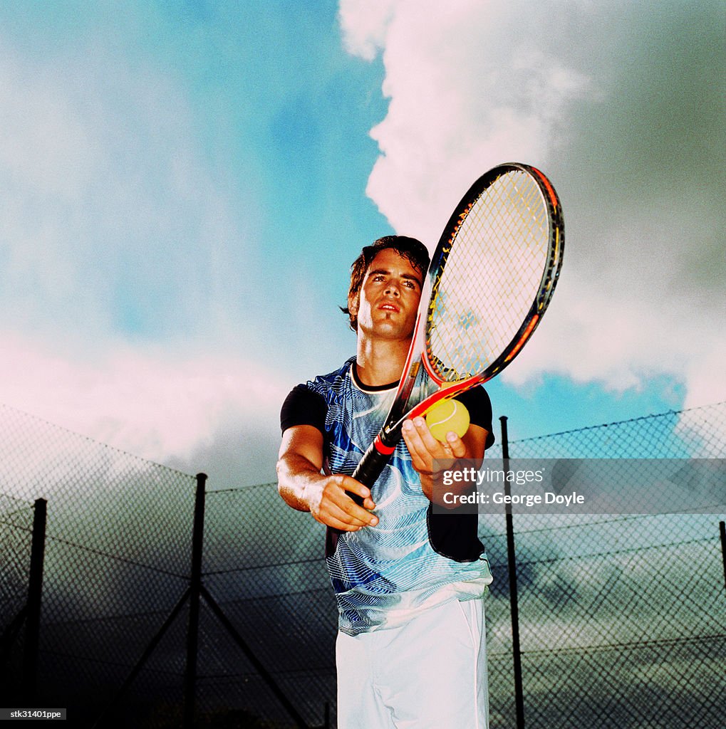 Low angle close-up of a man about to serve in a game of tennis