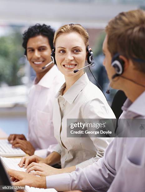 two businessmen and a businesswoman wearing headsets in an office - communication occupation stock pictures, royalty-free photos & images