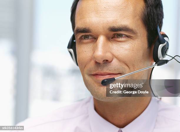 close-up of a businessman wearing a headset in an office - communication occupation stock pictures, royalty-free photos & images