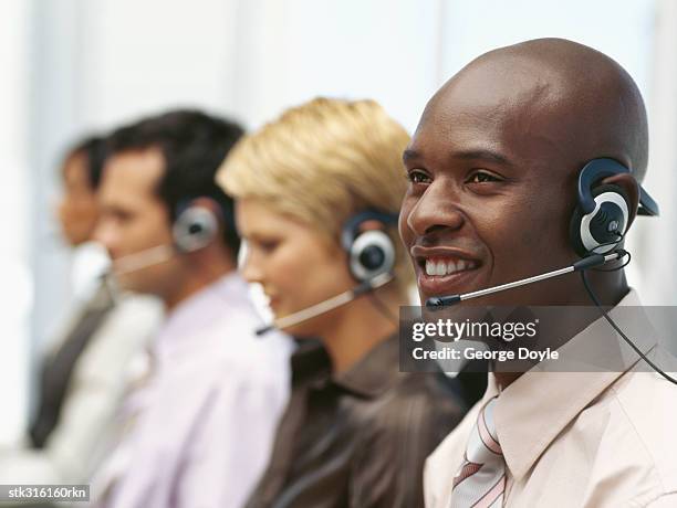 side profile of four business executives wearing headsets in an office - communication occupation stock pictures, royalty-free photos & images