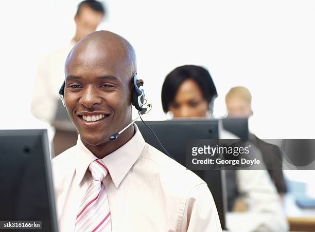 businessman wearing a headset sitting in front of computer - communication occupation stock pictures, royalty-free photos & images