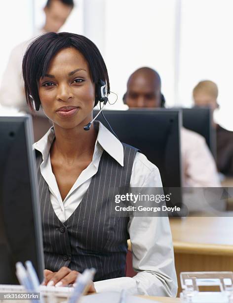 portrait of a businesswoman wearing a headset and sitting in front of a computer in an office - communication occupation stock pictures, royalty-free photos & images