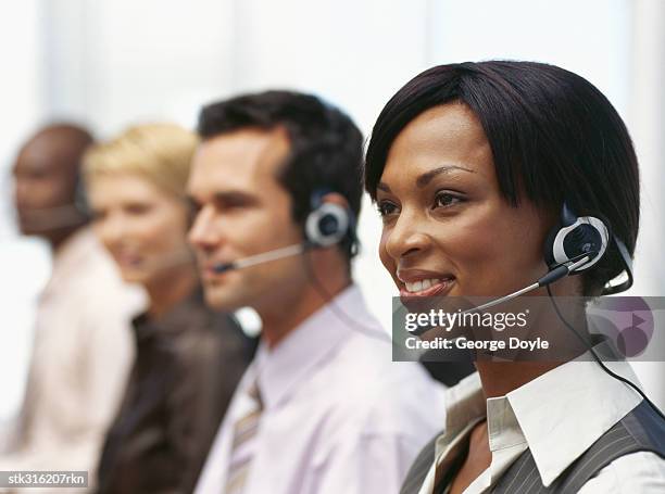 side profile of four business executives wearing headsets and sitting in a row - communication occupation stock pictures, royalty-free photos & images