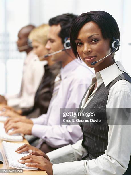 portrait of a businesswoman wearing a headset with three businesses executives sitting next to her - métier de la communication photos et images de collection