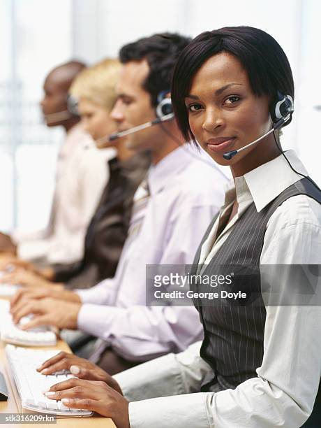 portrait of a businesswoman wearing a headset with three businesses executives sitting next to her - next stockfoto's en -beelden
