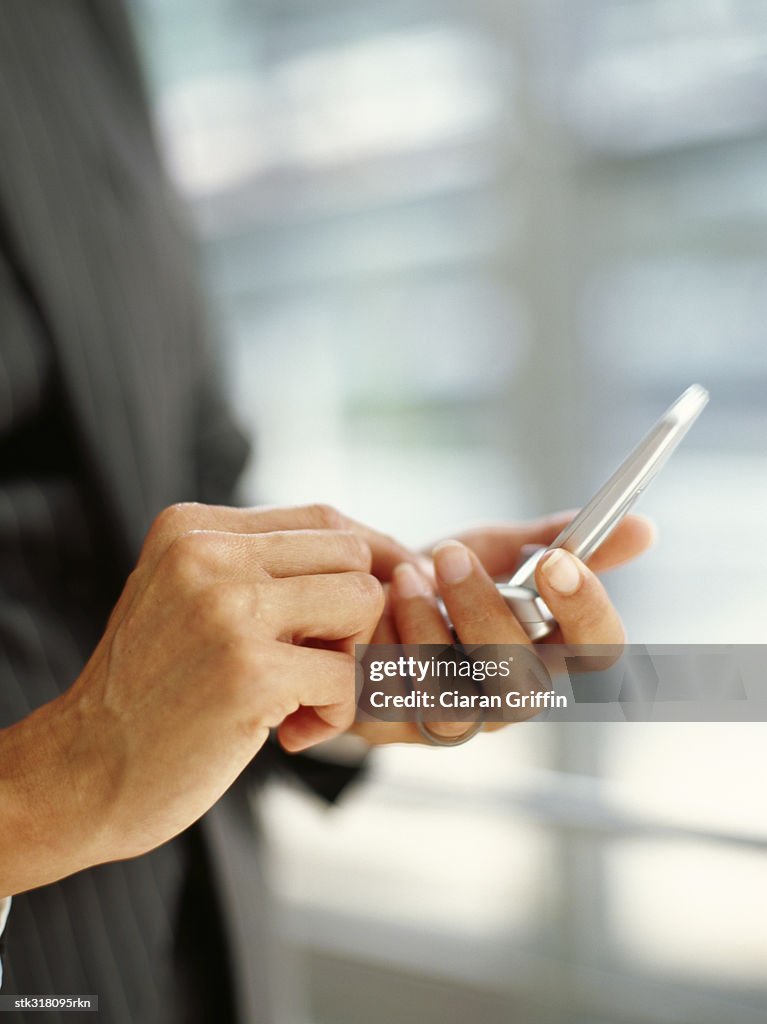 Mid section view of a person using a mobile phone in an office