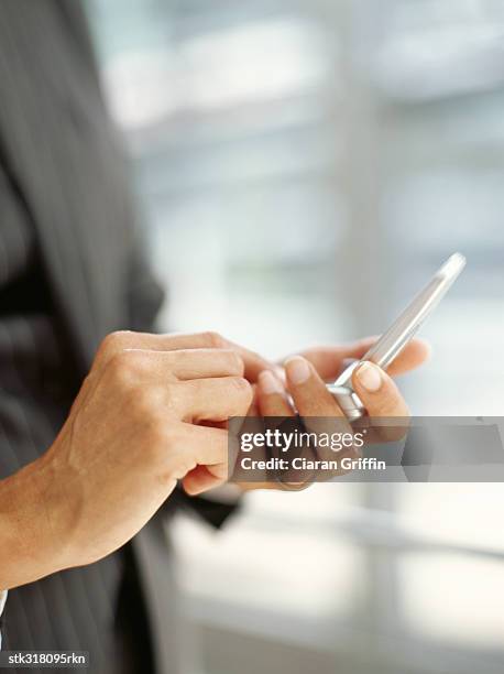 mid section view of a person using a mobile phone in an office - hand holding flip phone imagens e fotografias de stock