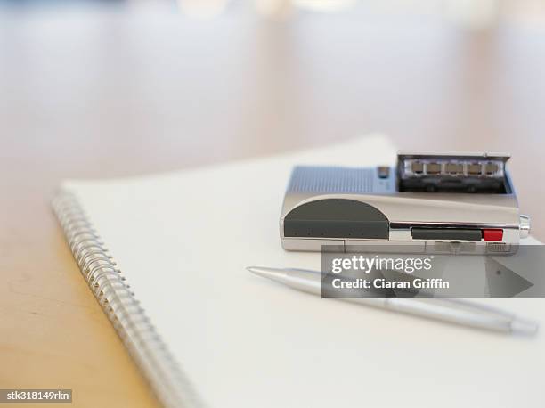 close-up of a pen and a personal stereo on a spiral notebook in an office - personal stereo stockfoto's en -beelden