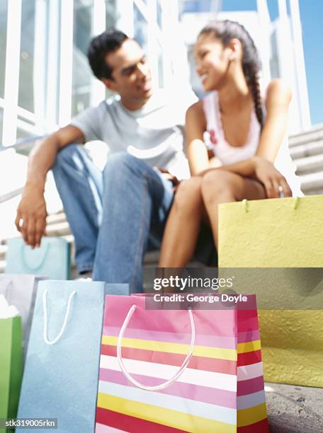 low angle view of a young couple sitting on steps - hand on knee stock pictures, royalty-free photos & images