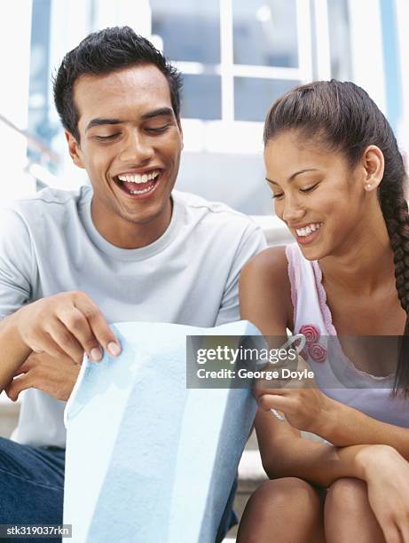young couple looking in a shopping bag - hand on knee stock pictures, royalty-free photos & images