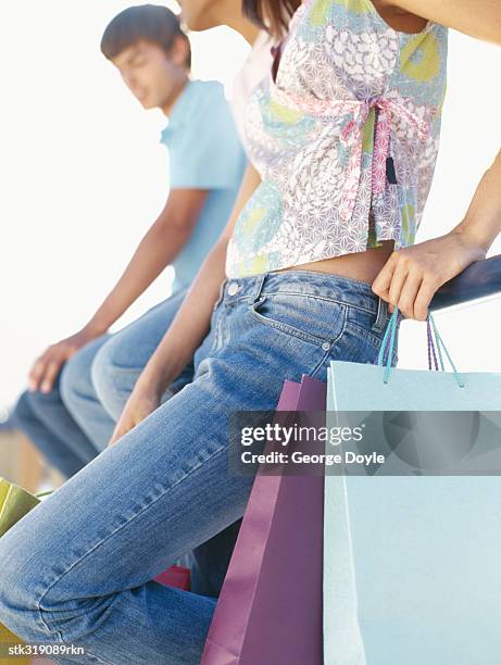 side profile of a young couple sitting on a railing - hand on knee stock pictures, royalty-free photos & images