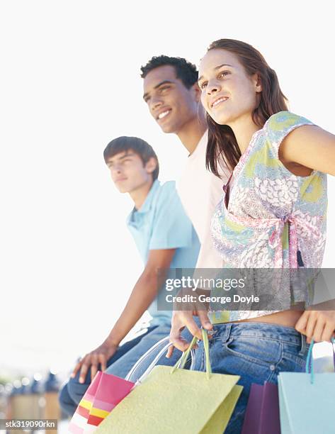 two young men and a young woman sitting on a railing - hand on knee stock pictures, royalty-free photos & images