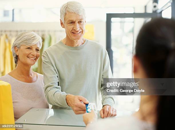 mature woman making payment through a credit card - maschio con gruppo di femmine foto e immagini stock