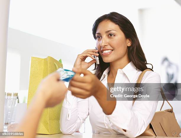 young woman making payment through a credit card - equipamento de varejo - fotografias e filmes do acervo