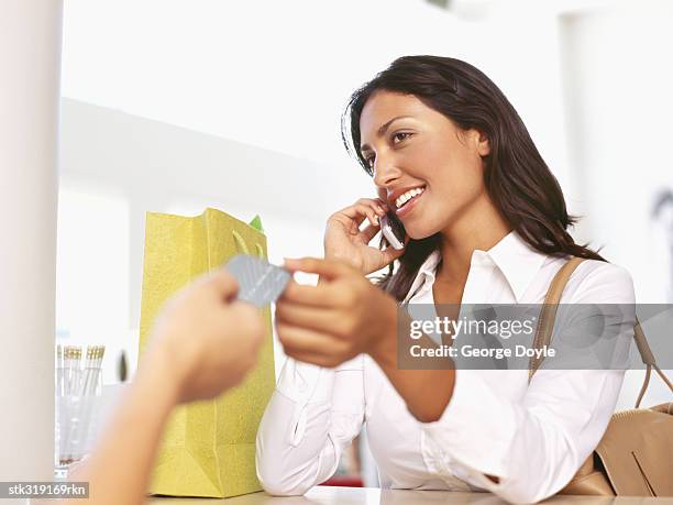 young woman making payment through a credit card - equipamento de varejo - fotografias e filmes do acervo