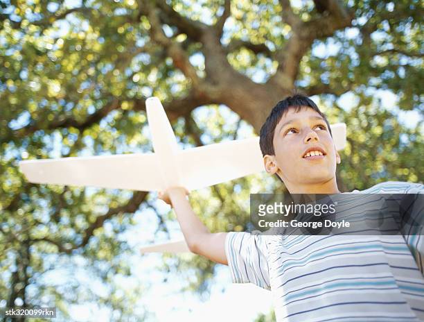 low angle view of a boy playing with a toy airplane - modell stock pictures, royalty-free photos & images