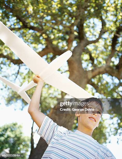 low angle view of a boy playing with a toy airplane - modell stockfoto's en -beelden