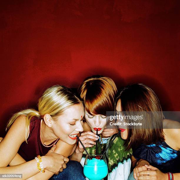 close-up of three women drinking with straws from a single cocktail in a bar - bar ストックフォトと画像