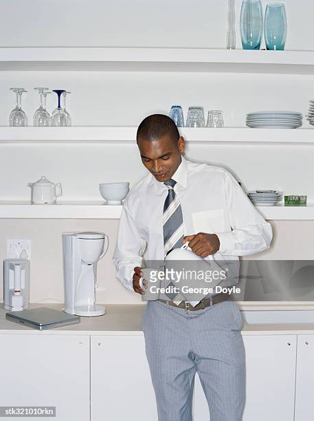 businessman pouring coffee from a kettle in an office - kettle - fotografias e filmes do acervo