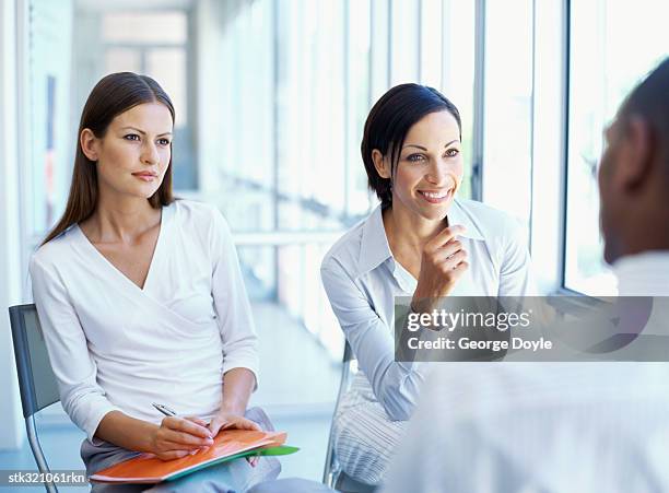 two businesswomen and a businessman discussing work in an office - maschio con gruppo di femmine foto e immagini stock